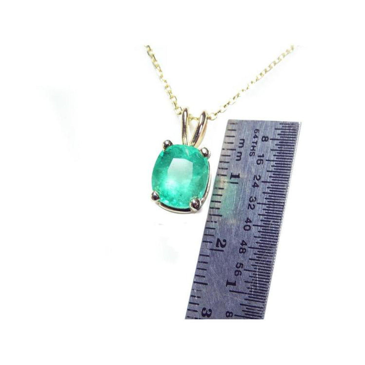 Cushion cut natural emerald solitaire pendant in 14K yellow gold with ruler for scale.