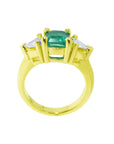 A lateral view of a 18k yellow gold emerald and trillion diamonds ring for women