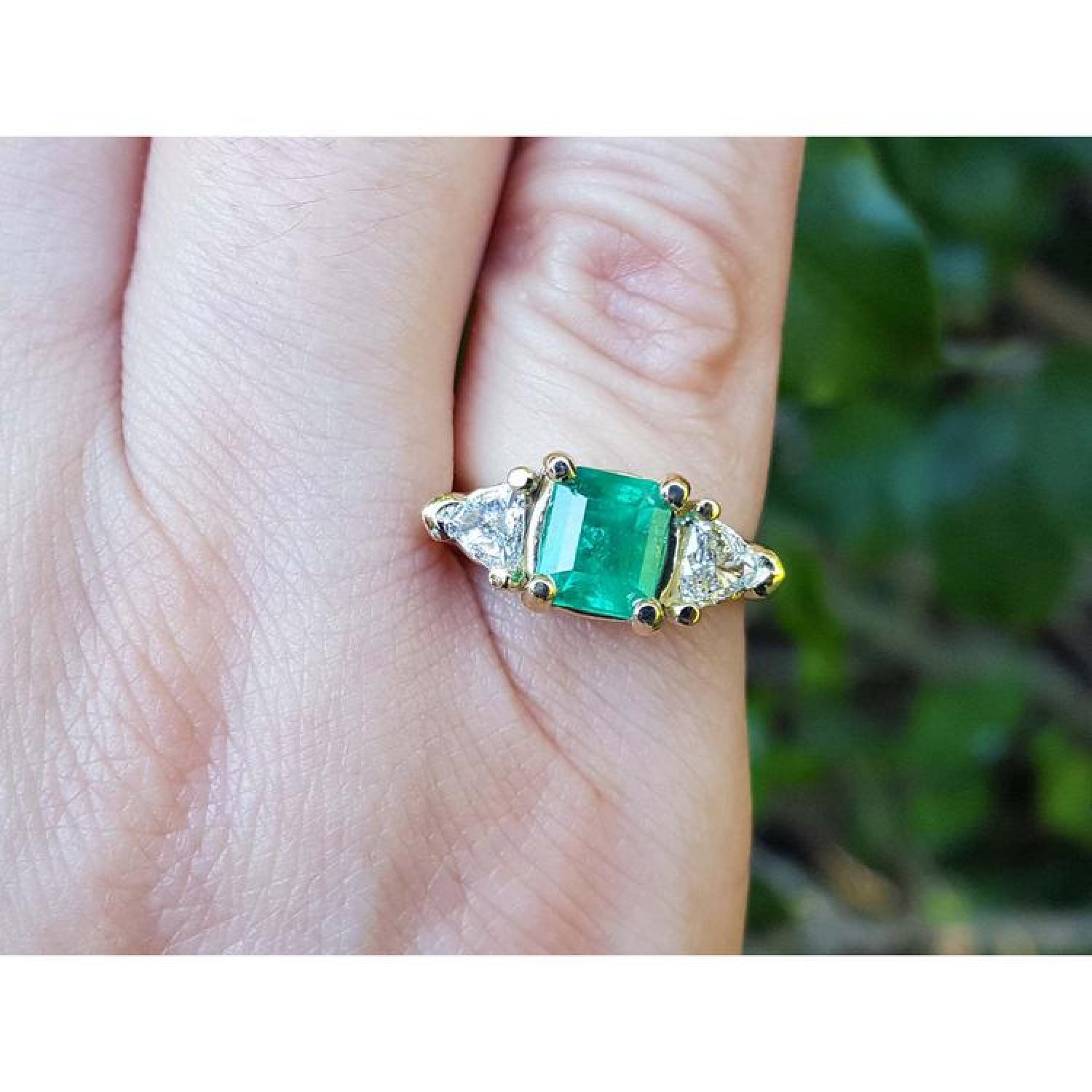 1.47 ct emerald-cut Colombian emerald ring with trillion diamonds in 18k yellow gold.