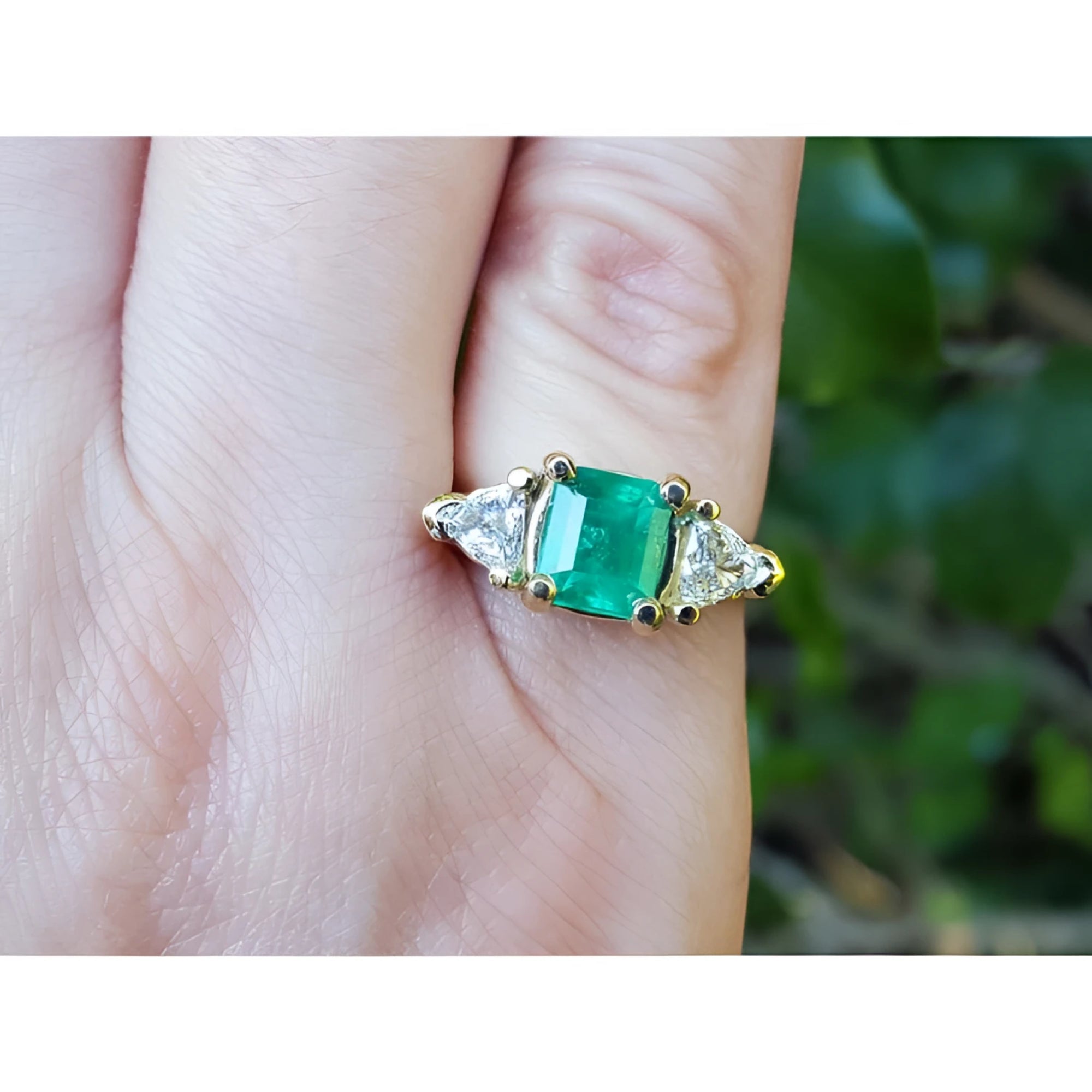 1.47 ct emerald-cut Colombian emerald ring with trillion diamonds in 18k yellow gold.