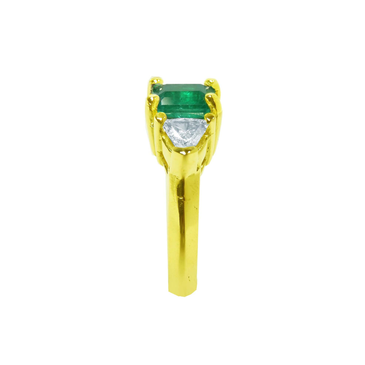 The 18k yellow gold natural colombian emerald and trillion diamonds ring for women in a side profile view.