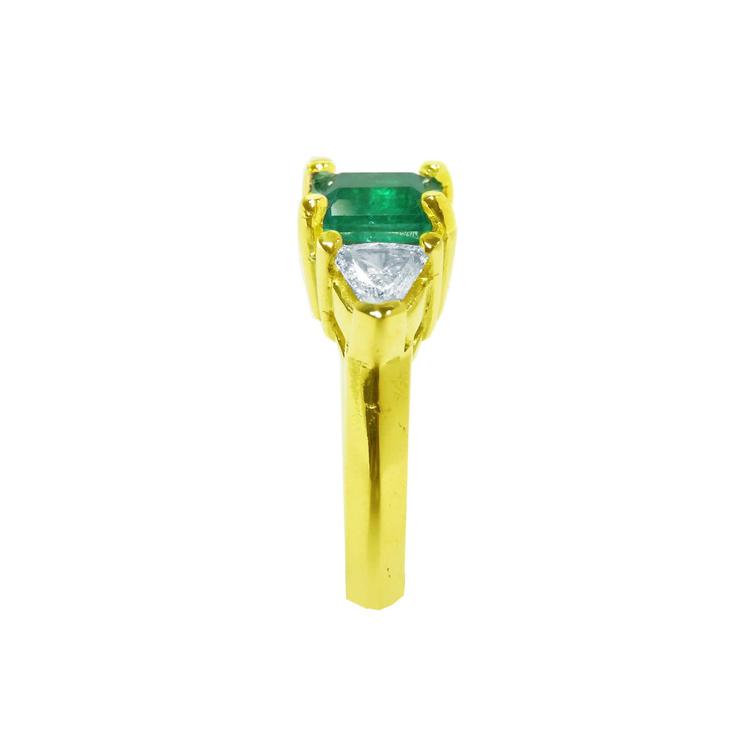 The 18k yellow gold natural colombian emerald and trillion diamonds ring for women in a side profile view.