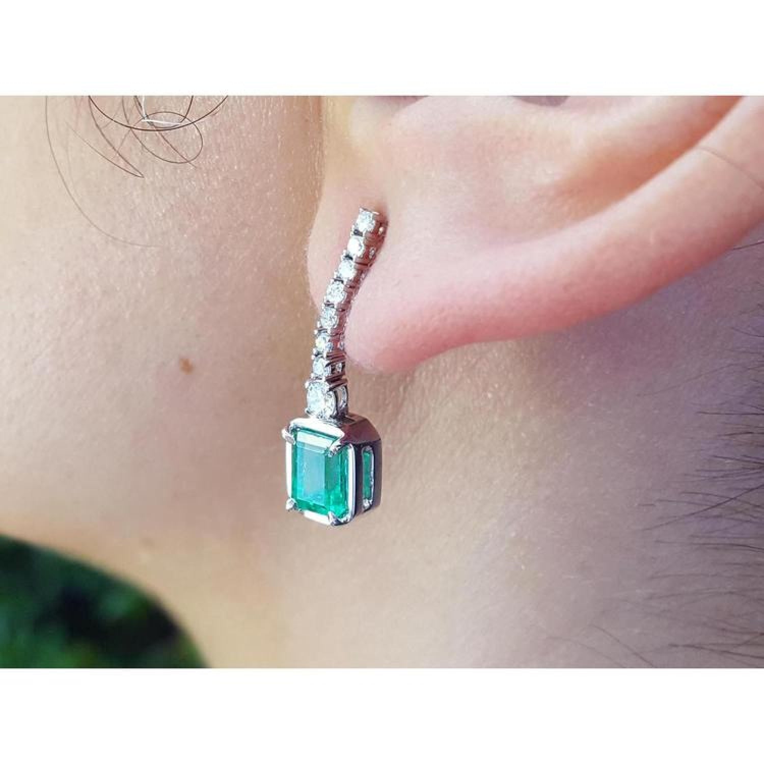 18K white gold dangling earrings with emerald-cut Colombian emeralds and diamond studs.