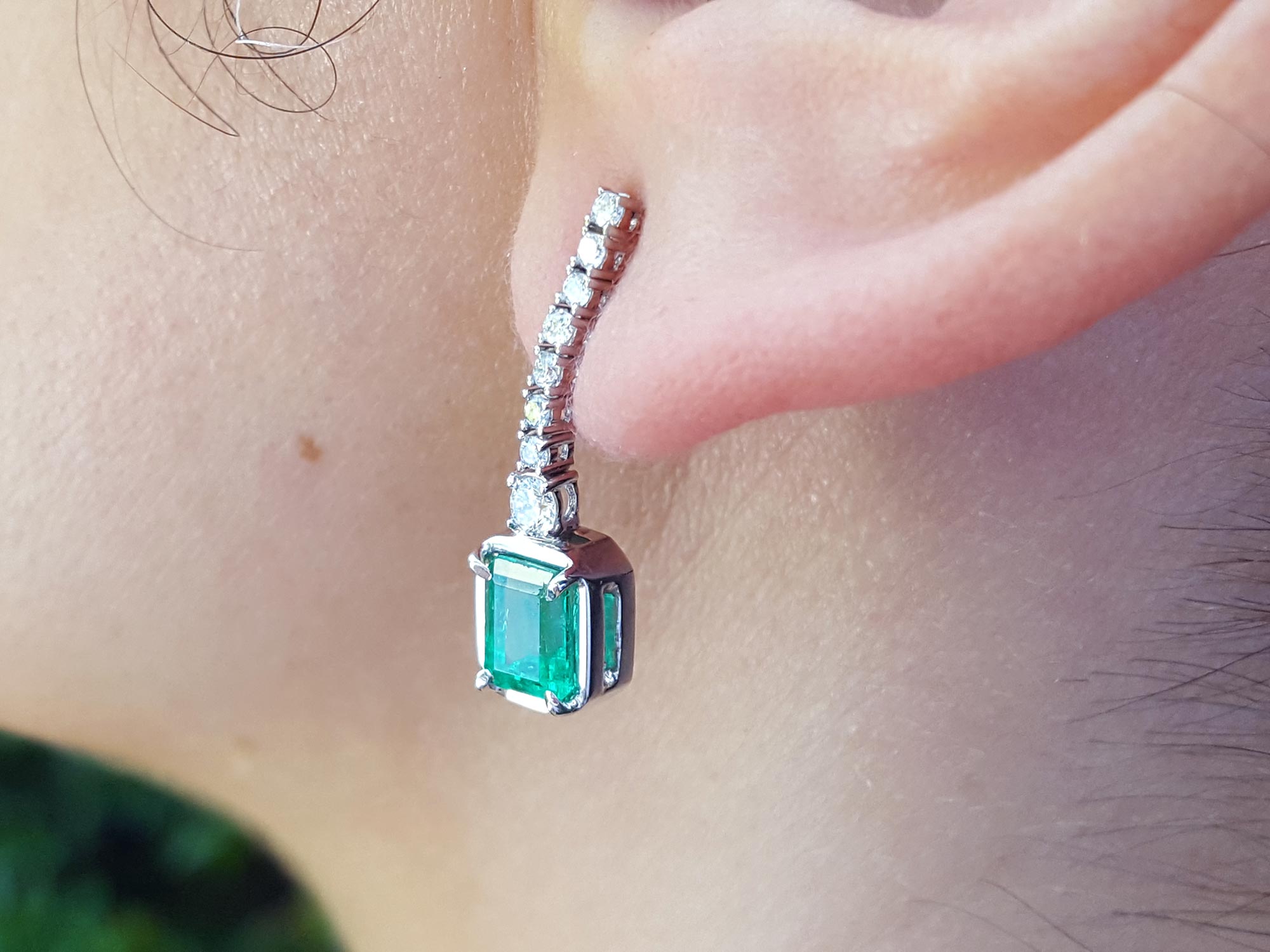 Close-up of a Mother’s Day emerald earring on an ear with a blurred background