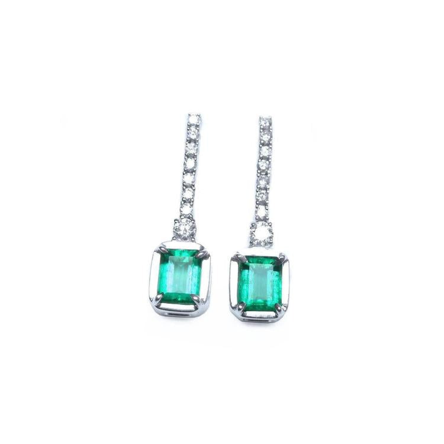 18K white gold dangling emerald-cut emerald earrings with diamond-studded lines.