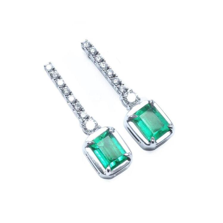 Pair of emerald dangle earrings with 14k white gold settings right side position top view