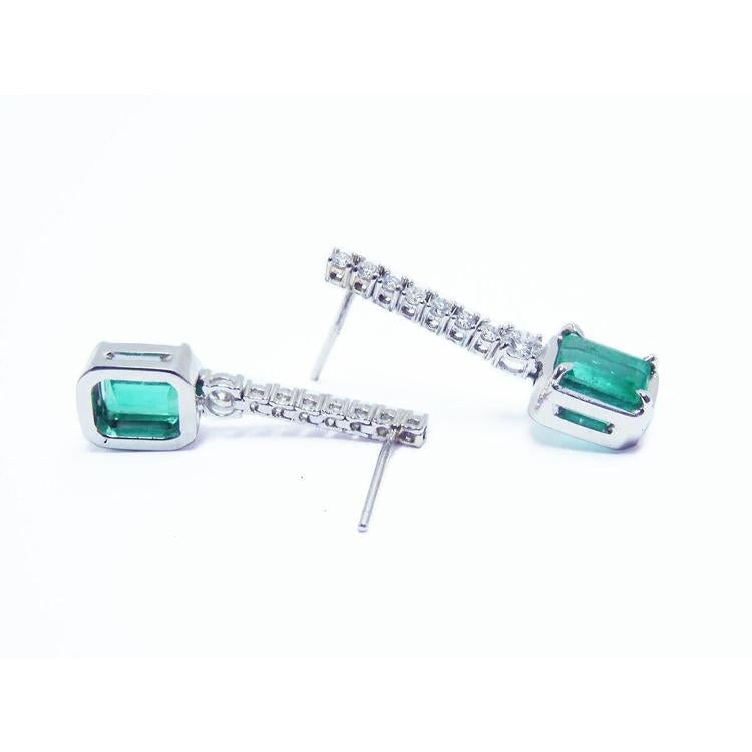 18K white gold dangling emerald-cut emerald earrings with diamond-studded straight lines.