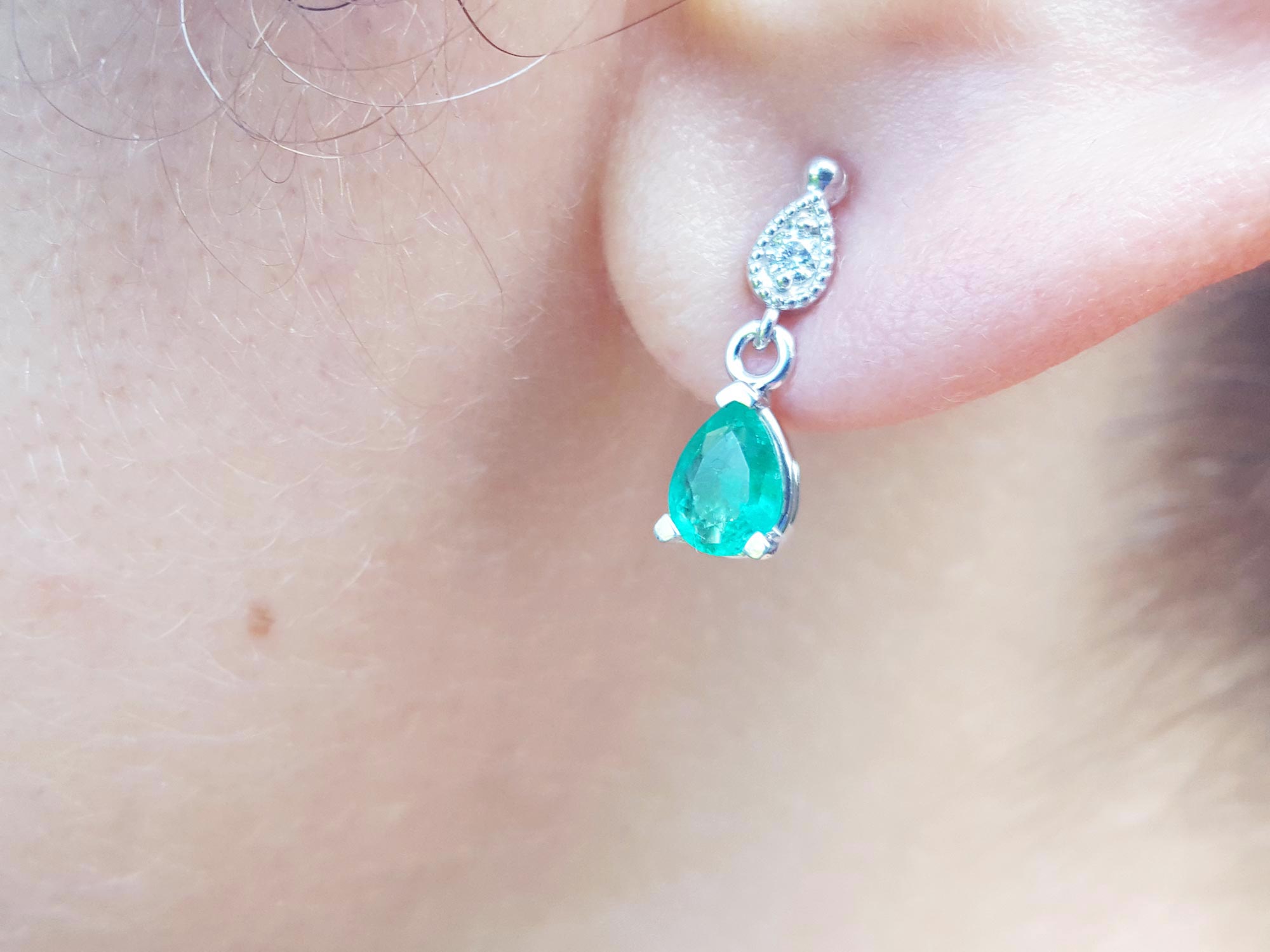 Close-up of an emerald teardrop earrings on a woman's ear