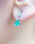 Woman's earlobe wearing a pear-cut emerald earrings left side profile