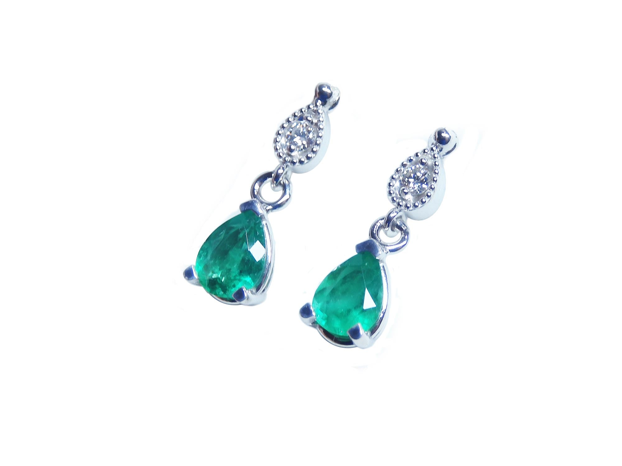 Left side profile of a pair of pear cut emerald dangle earrings in 14l white gold