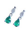 Left side profile of a pair of pear cut emerald dangle earrings in 14l white gold