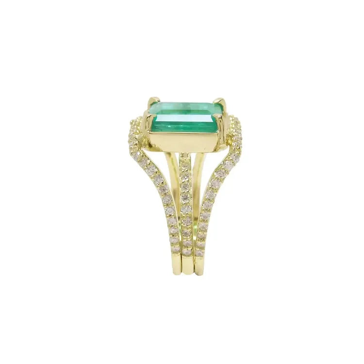 Un perfil lateral de este anillo con esmeralda para dama se ve la esmeralda en la parte superior de tres aros con diamantes.