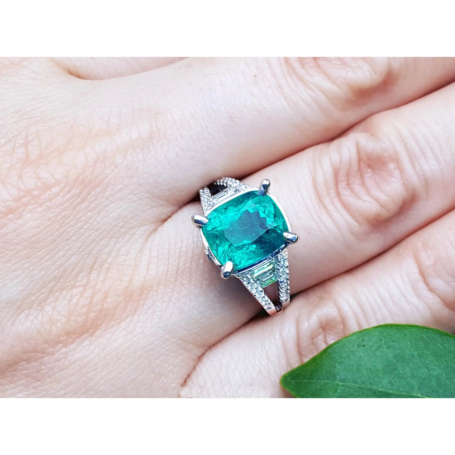 vista cercana de un anillo de compromiso con esmeralda colombiana en oro blanco de 18k, exhibiendo como luce en dedo.