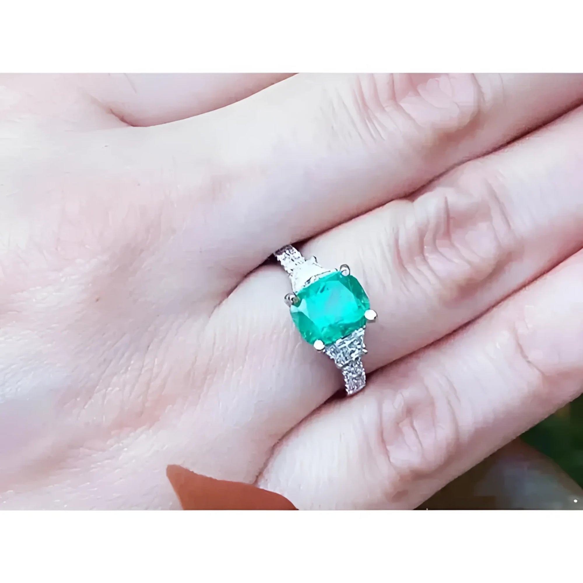 Anillo de compromiso de oro blanco 18k con esmeralda colombiana y diamantes trapezoide.