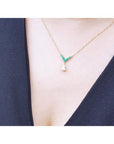 14K gold necklace with pear-cut diamond and V-shaped emerald centerpiece on a model.