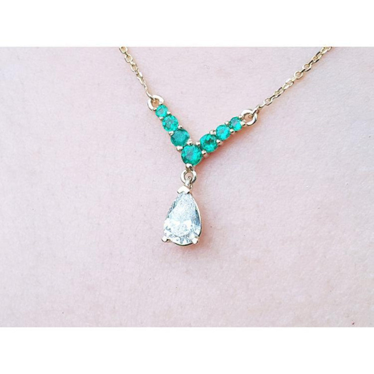 14K gold necklace with a 0.69 ct pear diamond and 0.35 ct round emeralds in a V-shape.