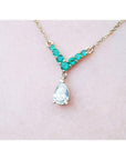 14K gold necklace with a 0.69 ct pear diamond and 0.35 ct round emeralds in a V-shape.