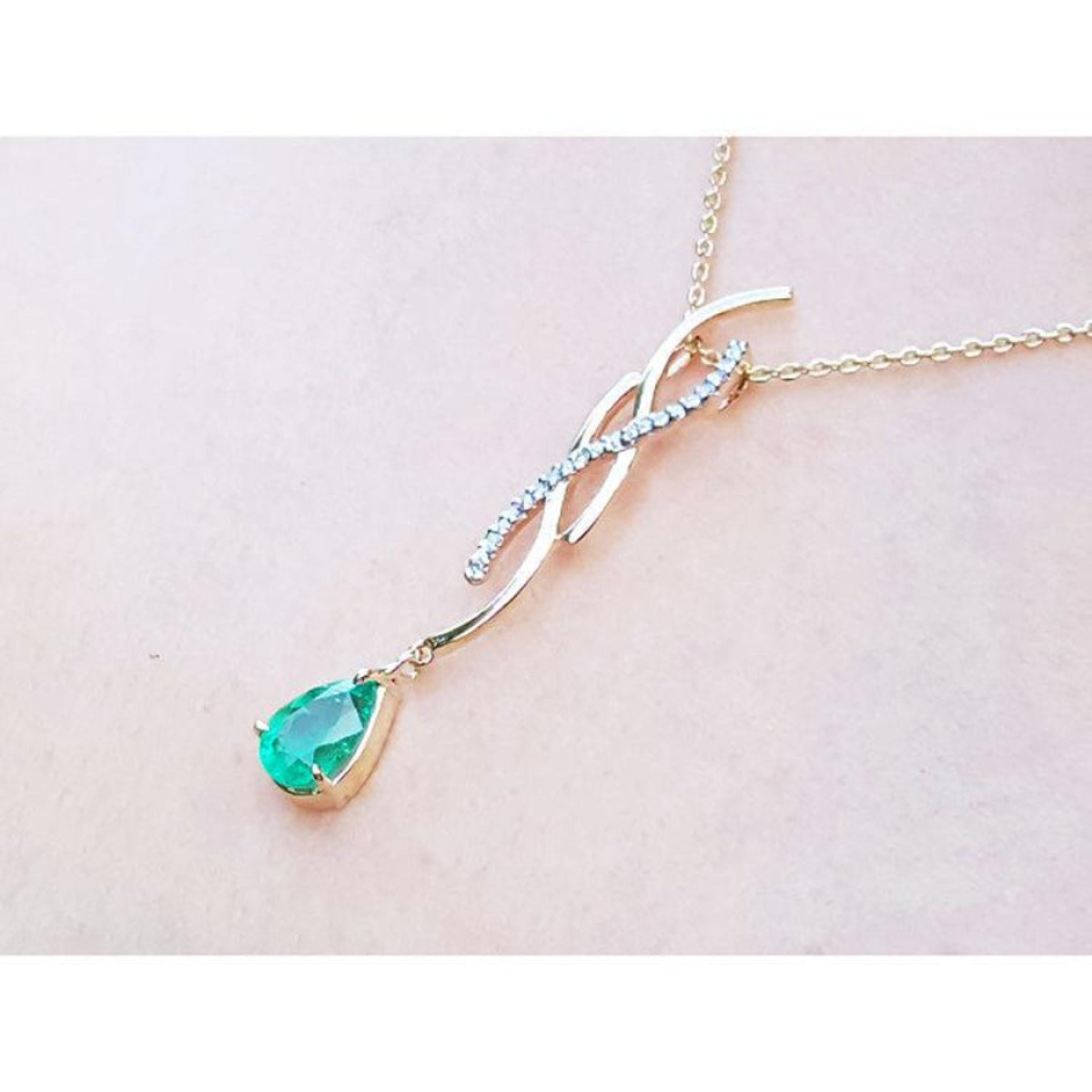 14K yellow gold twisted slider necklace with a pear-shaped emerald and diamond accents.