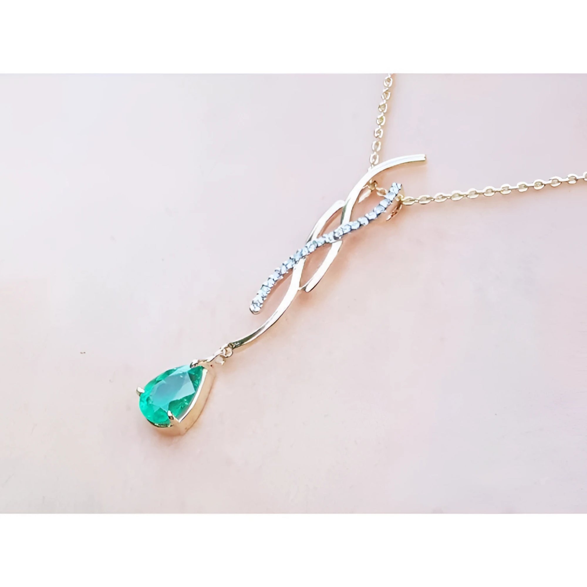 14K yellow gold twisted slider necklace with a pear-shaped emerald and diamond accents.