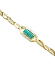 Gold bracelet with a baguette cut natural emerald and diamonds on a white background.
