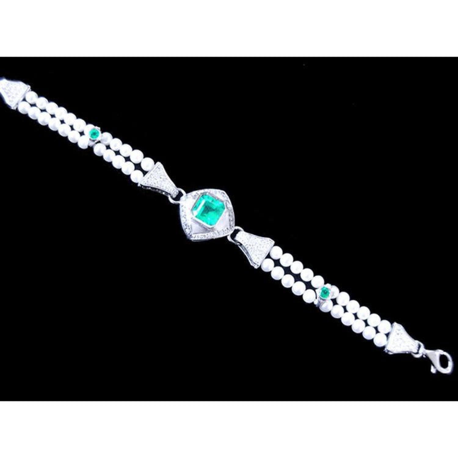 18K white gold bracelet with a central emerald, accented by pearls and small green emeralds.