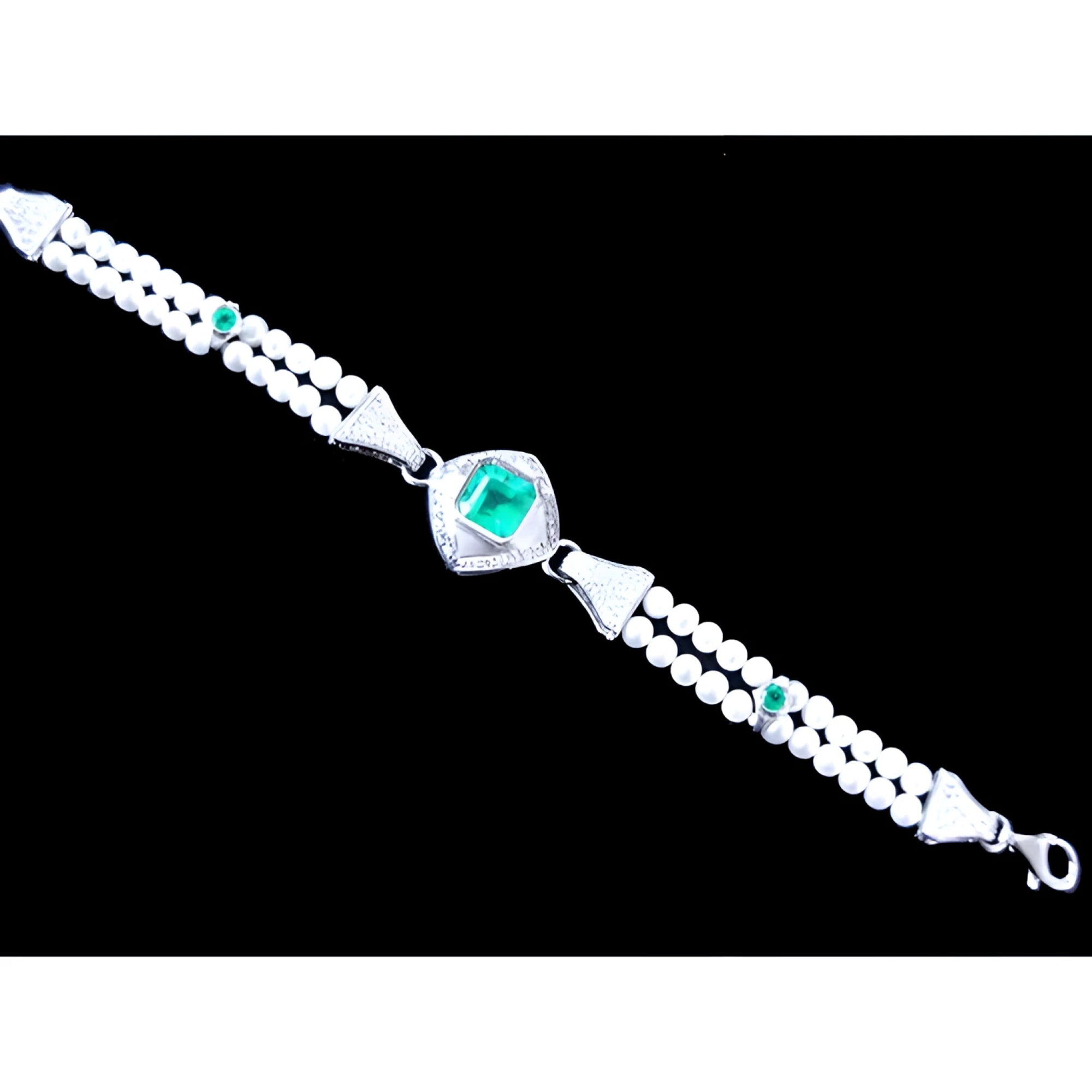 18K white gold bracelet with a central emerald, accented by pearls and small green emeralds.