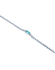 A distant view of a white gold bracelet with a central emerald gemstone on a white background.