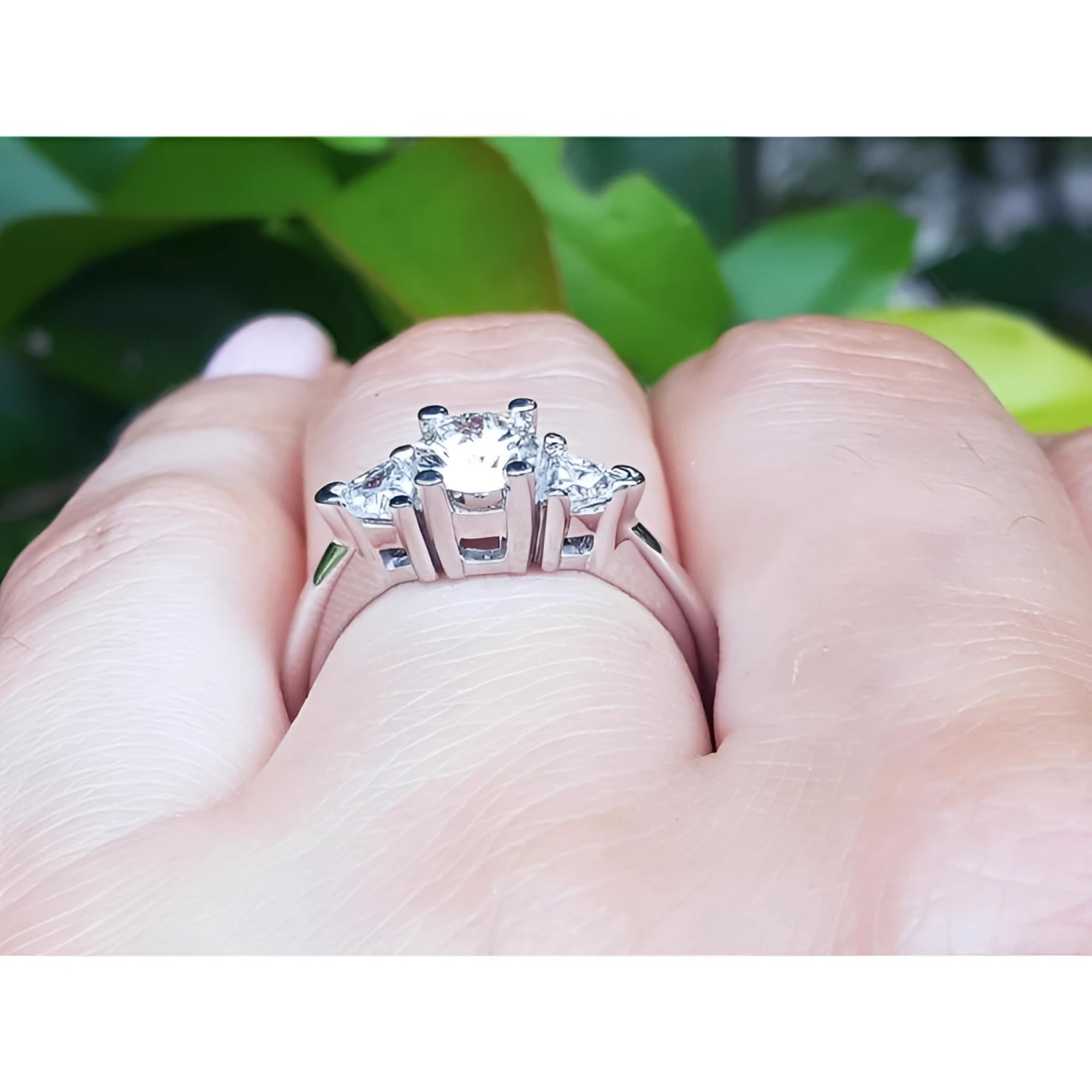 14K white gold engagement ring with a round center diamond and two trillion side diamonds.