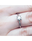 Round cut diamond solitaire engagement ring in 14K white gold, worn on a finger.