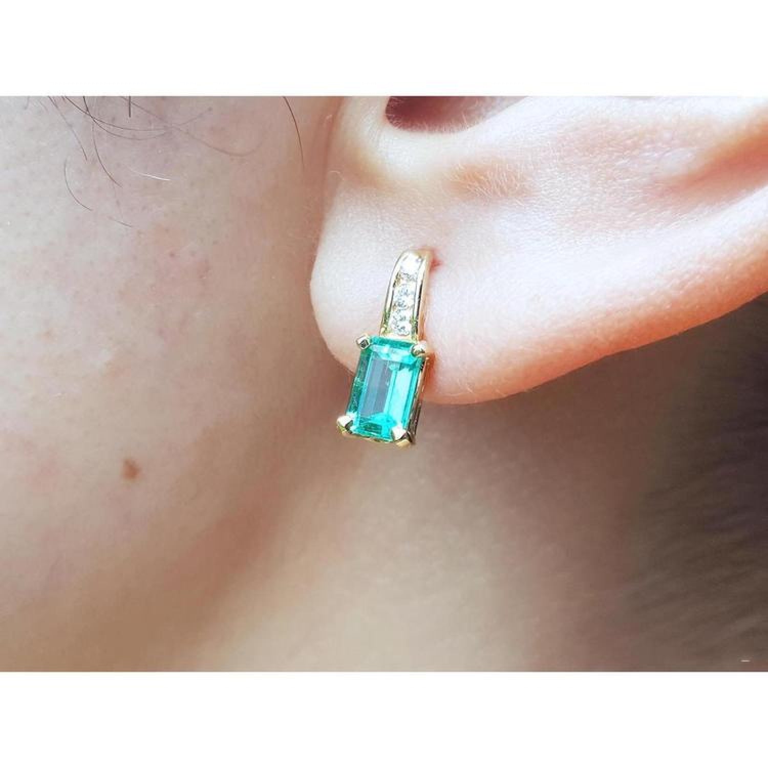 14K yellow gold emerald earring with baguette-cut emerald and diamond accents on an ear.