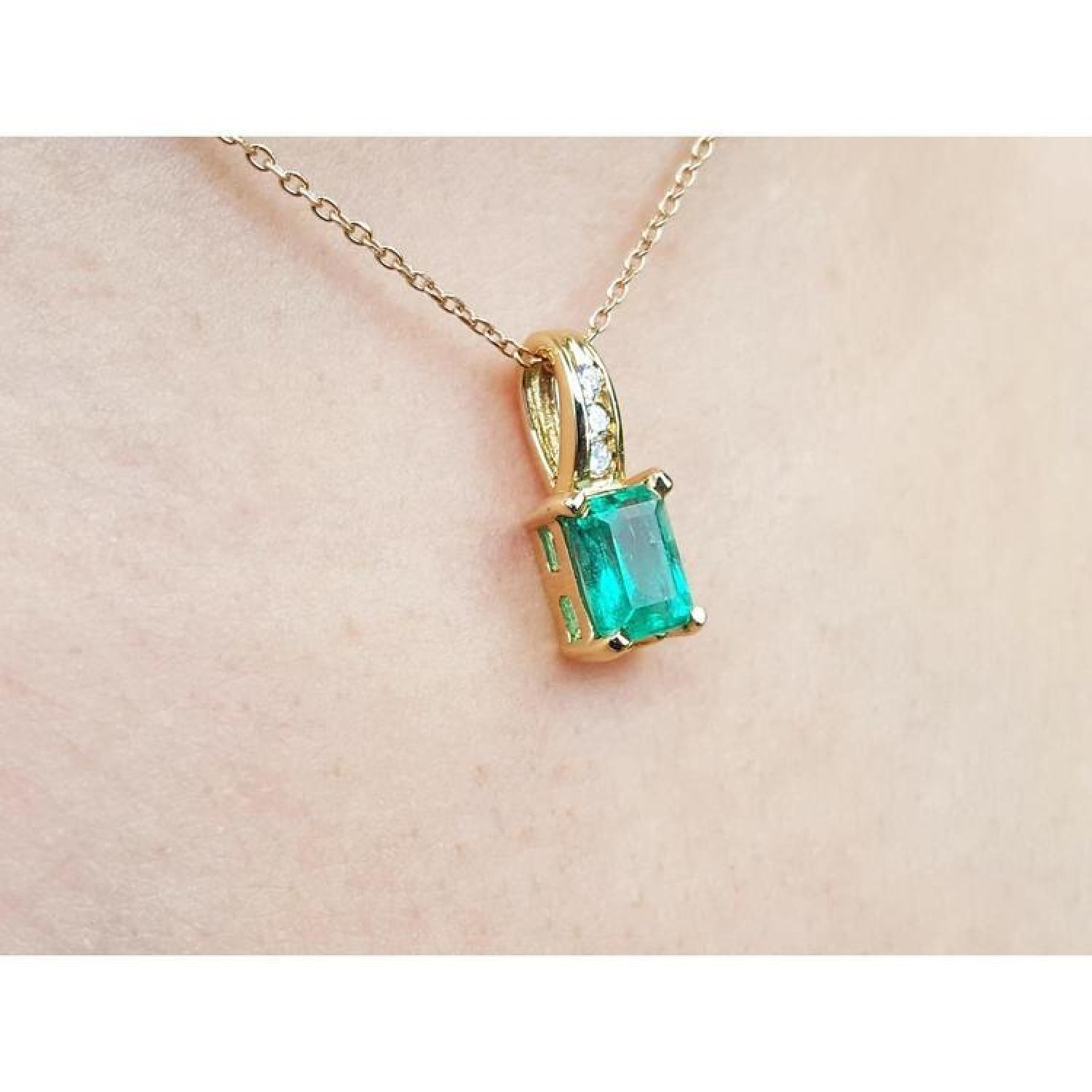 14K yellow gold pendant with an emerald-cut green emerald and diamond accents on a delicate chain.