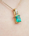 A right-side profile view of an emerald pendant on a skin background
