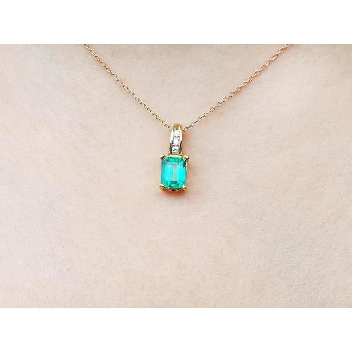 14K yellow gold pendant with a rectangular Colombian emerald and diamond accents on a delicate chain.