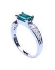 This emerald ring on top shows te lateral side and band with accent diamonds.