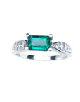 A Mother’s Day emerald white gold ring in an east-west style, featuring accent diamonds along the band.