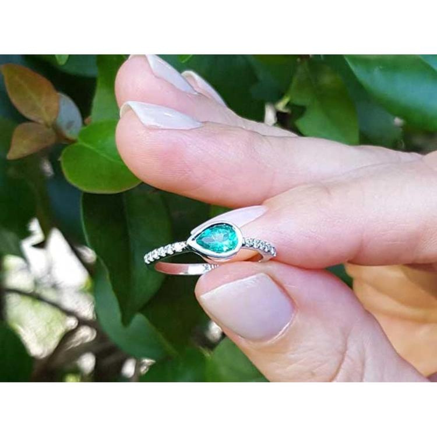 14K white gold ring with a bezel-set east-west teardrop emerald and prong-set accent diamonds.