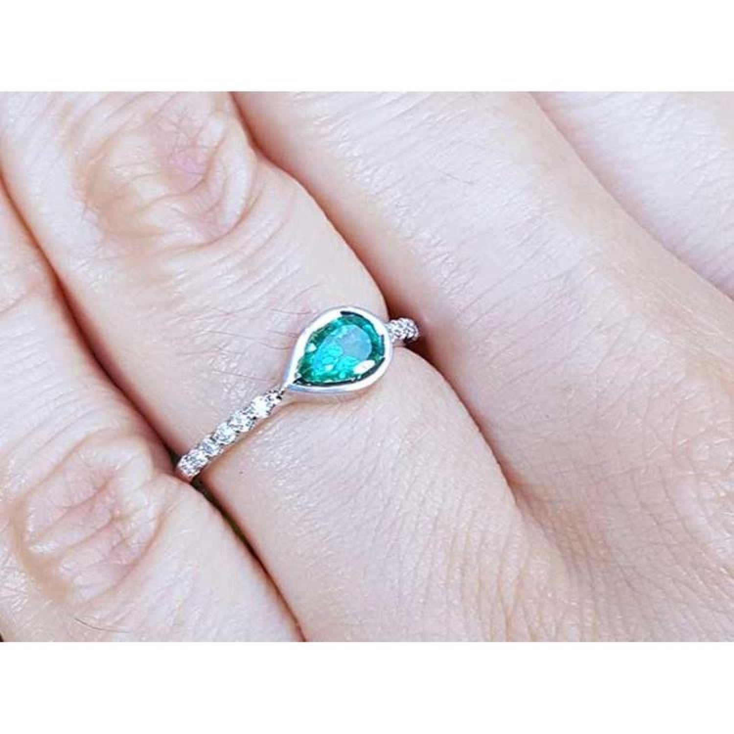 East-west teardrop emerald ring with bezel setting and diamond-accented 14K white gold band.