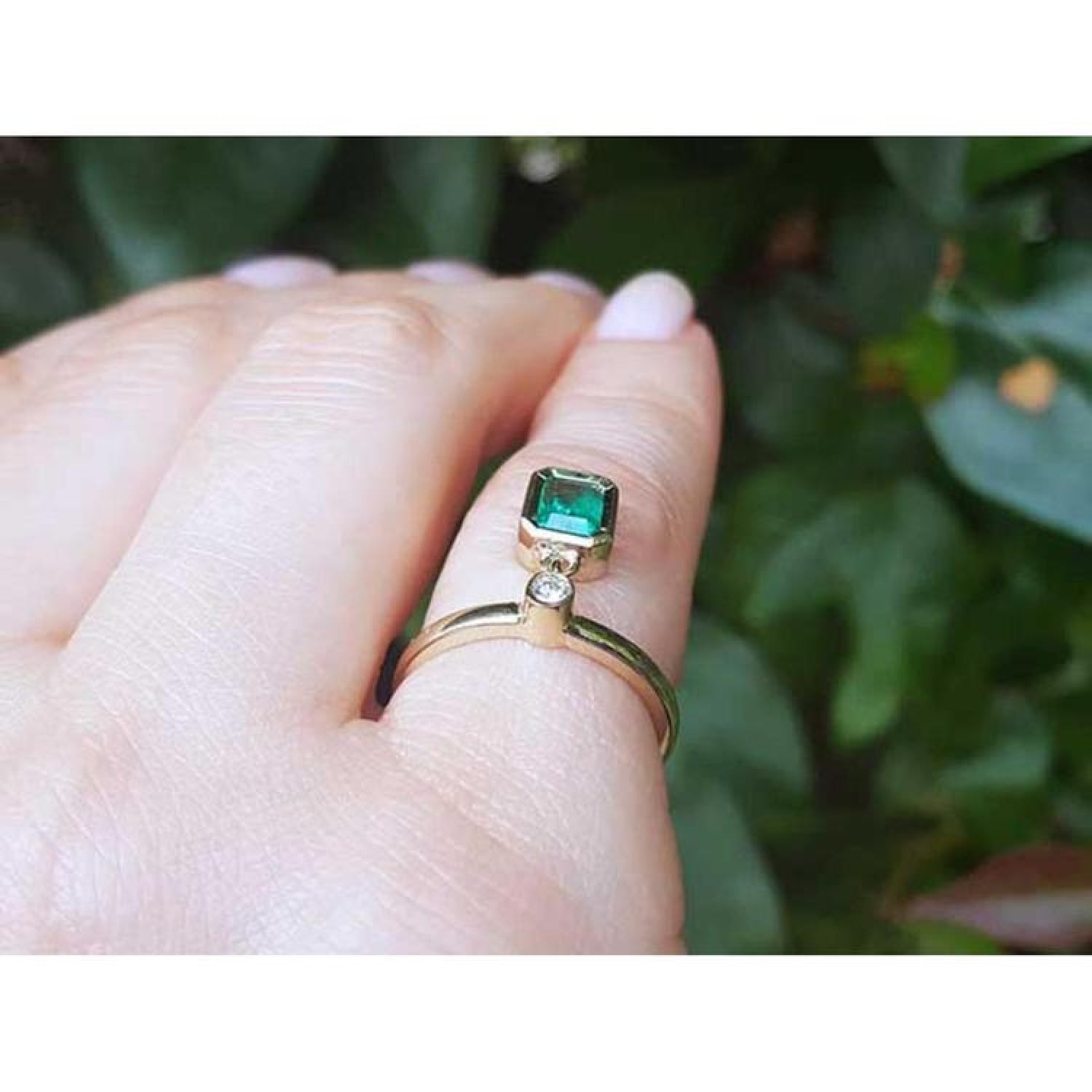 14K yellow gold ring with a bezel-set emerald dangle and a small diamond accent.