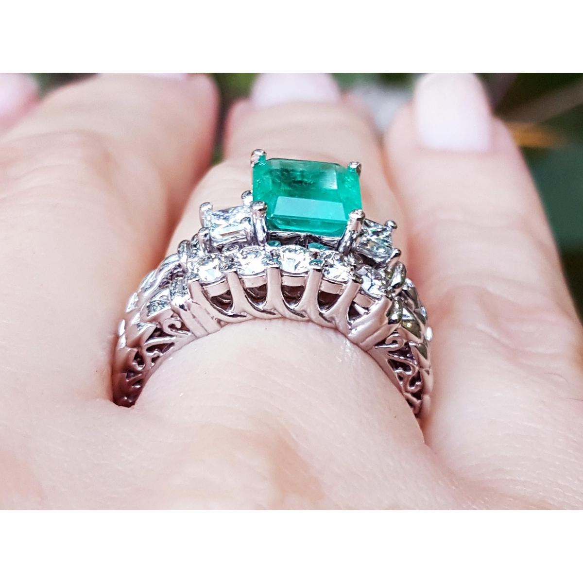 The gallery view of a diamond wedding match band of an emerald engagement ring on a person's hand.