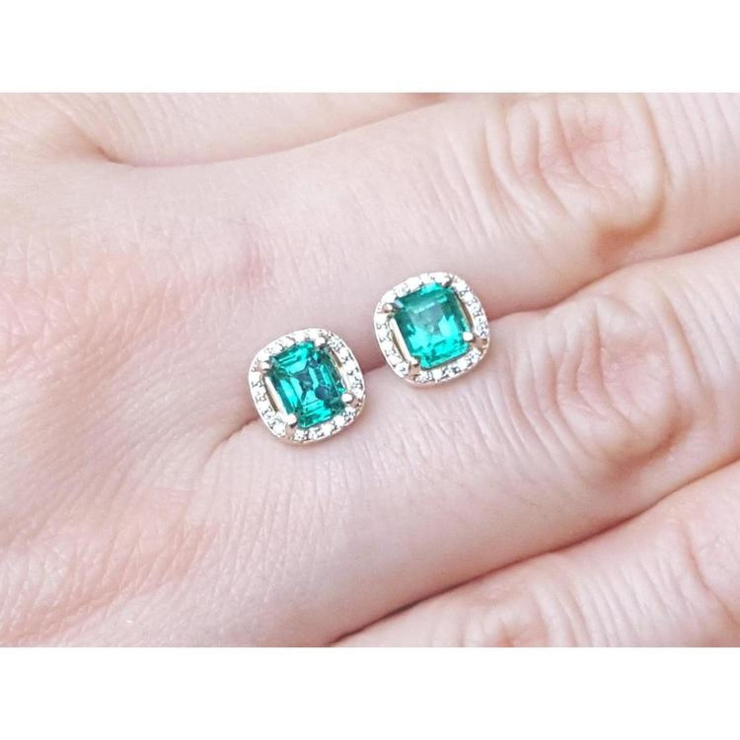 1.55 carat emerald stud earrings with halo diamonds set in 14K yellow gold.