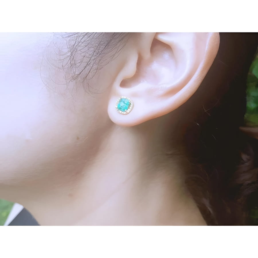 1.55 carat emerald stud earring with halo diamonds in 14K yellow gold on an ear.
