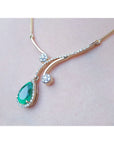 Colombian pear emerald necklace with diamonds in 18K yellow gold, worn on a person.