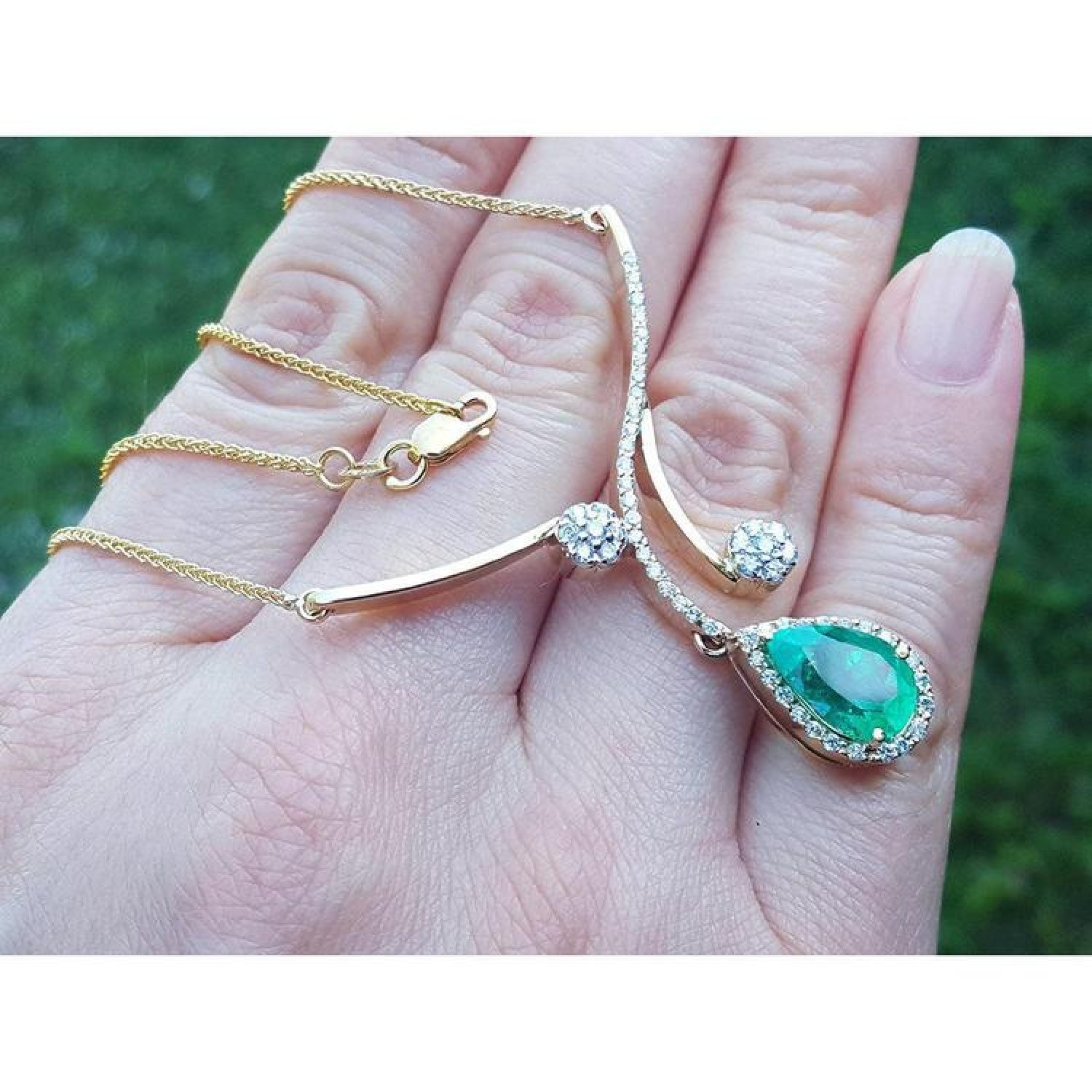 18K yellow gold necklace with a pear-shaped Colombian emerald and diamond clusters.