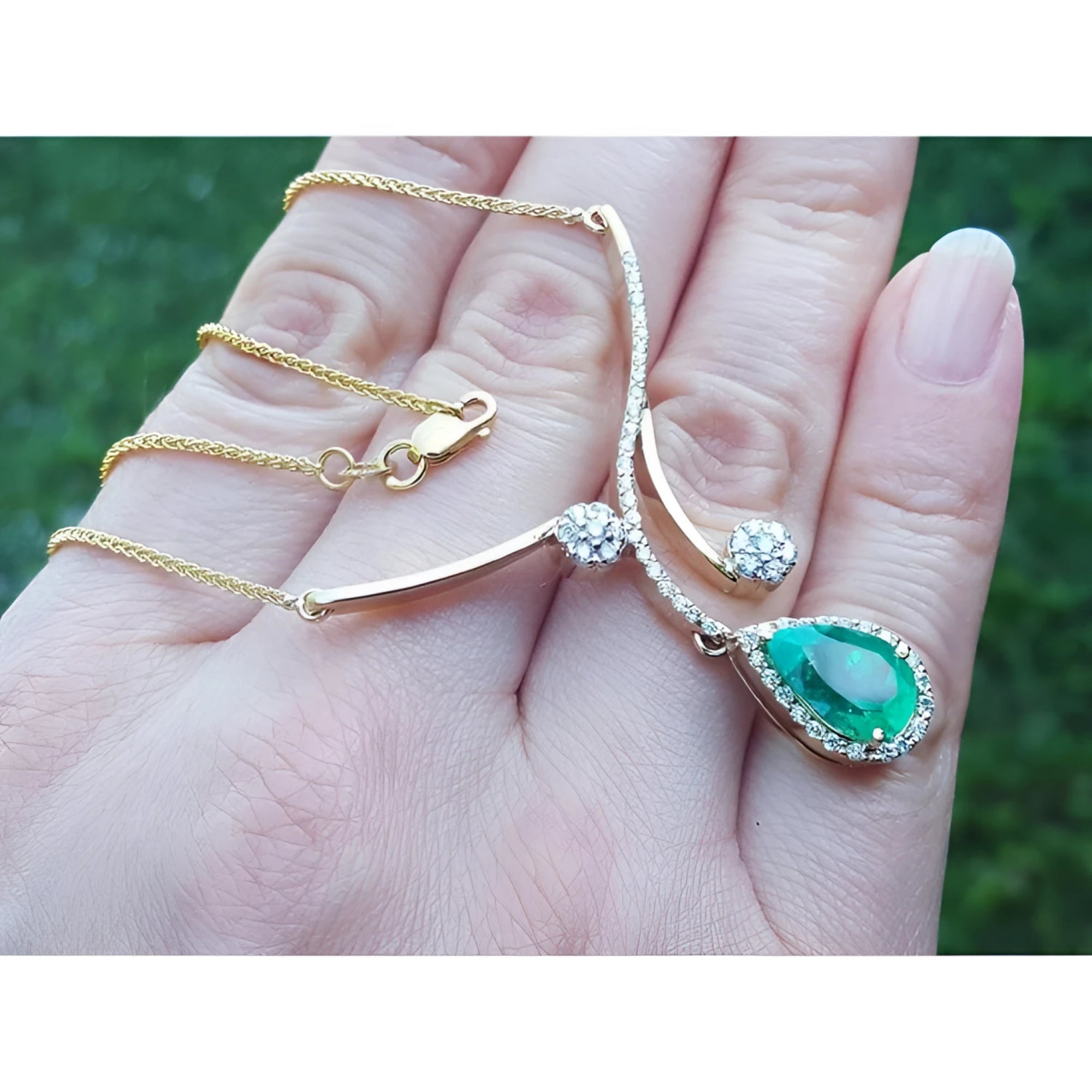 18K yellow gold necklace with a pear-shaped Colombian emerald and diamond clusters.