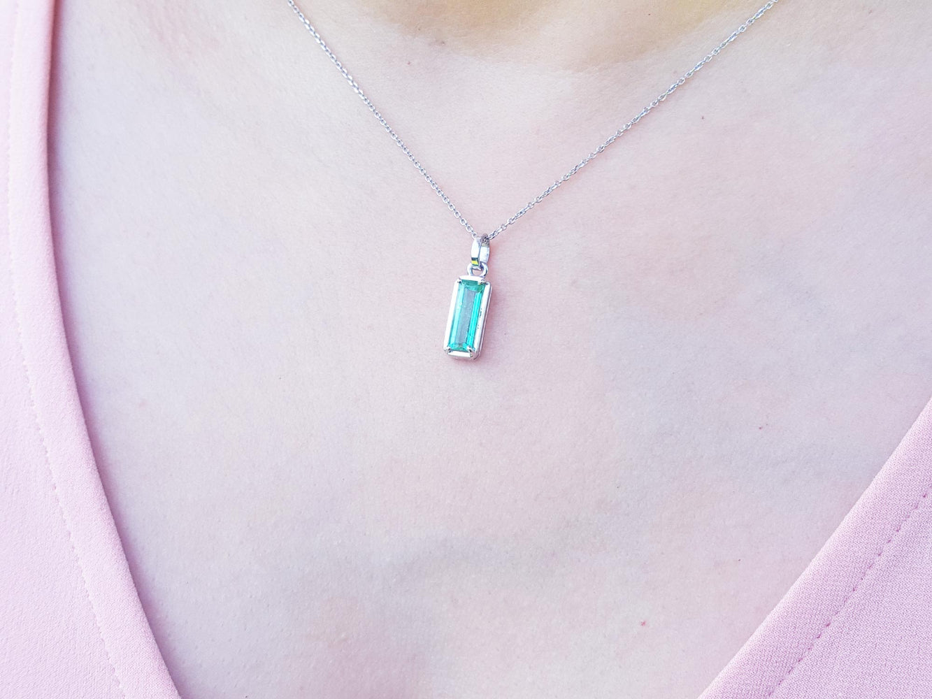 Necklace with a white gold emerald pendant on a person&#39;s chest