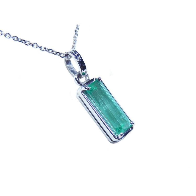 A natural colombian emerald pendant on a white gold chain displaying its topside and gallery profile.