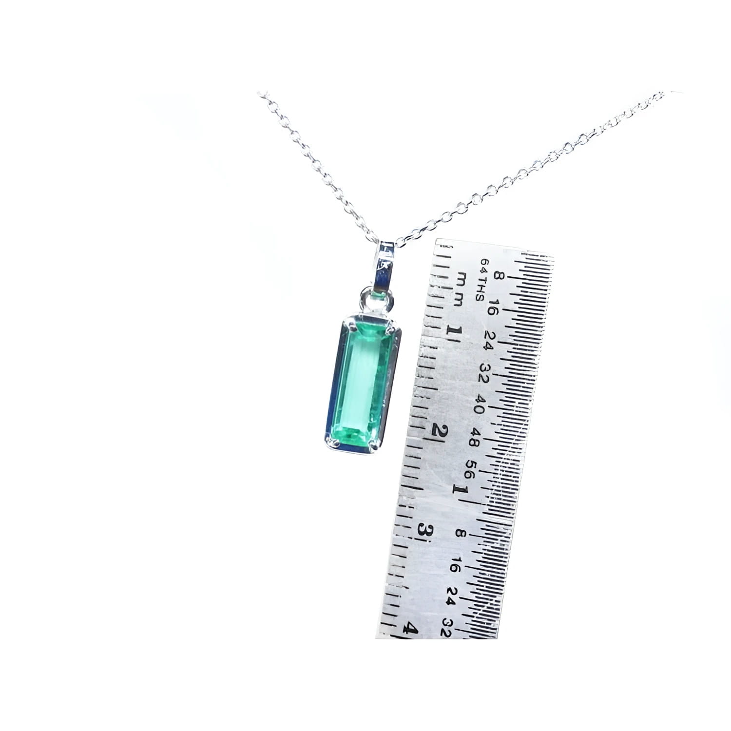 Rectangular emerald cut Colombian emerald solitaire pendant in 14K white gold with ruler for scale.