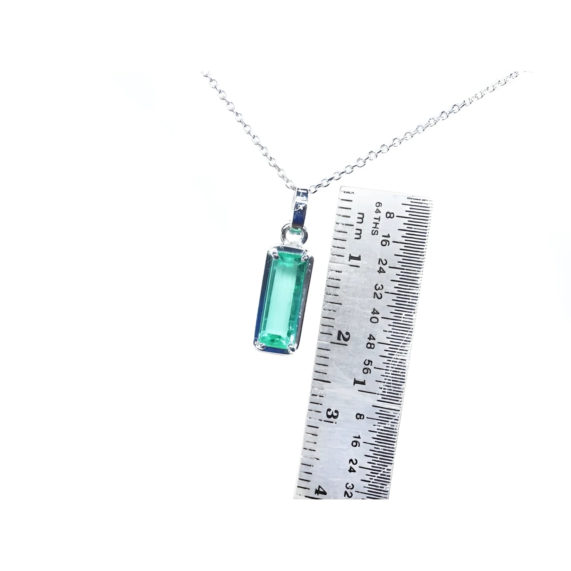 Rectangular emerald cut Colombian emerald solitaire pendant in 14K white gold with ruler for scale.