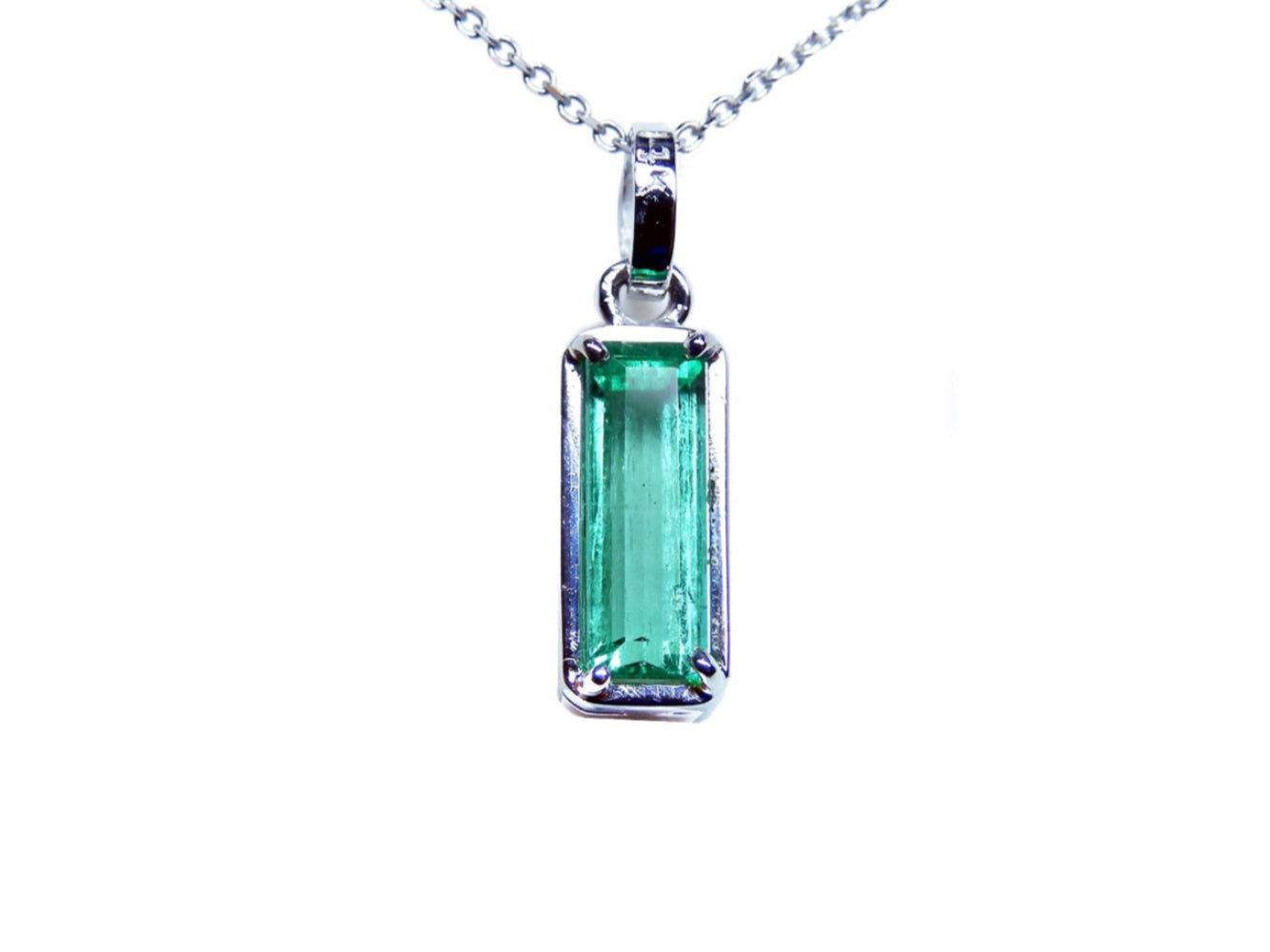 A solitaire emerald pendant on a white gold chain showing the topside view