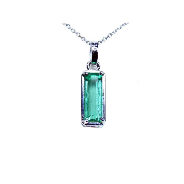 A solitaire emerald pendant on a white gold chain showing the topside view